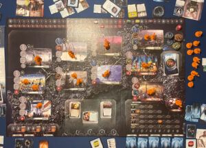 fotografía del tablero durante una partida al juego de mesa nueva angeles con miniaturas de color naranja, cartas y tokens distribuidos por la mesa en leganes